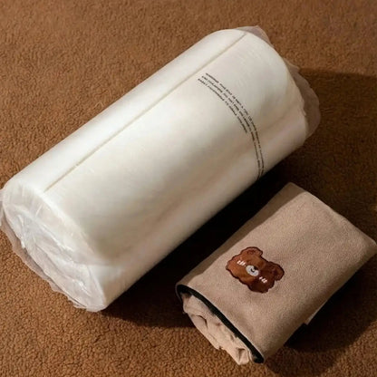 Vue du produit à la livraison : rouleau de mousse blanche comprimée sous plastique et housse en tissu beige pliée à côté.